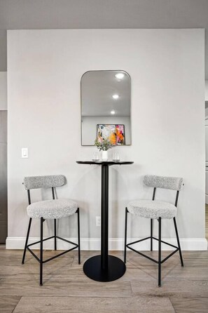 Une pièce moderne avec une table ronde, deux chaises, un miroir et un tableau accroché au mur.