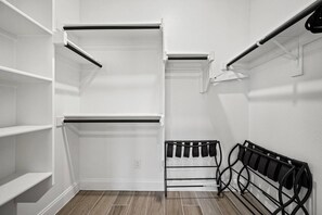 A walk-in closet with open shelves, a hanging rod, and a shoe rack.