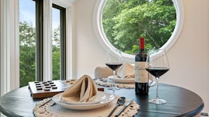 Una mesa de comedor con una botella de vino, dos copas de vino, un posavasos y una servilleta.
