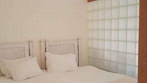 A bedroom with a bed, two pillows, a wooden headboard, and a window with frosted glass panels. - Spacious Studio at Estrela Da Luz, pools, indoor spa and gym. (Luz)