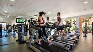 A gym with treadmills, weight machines, and a large screen displaying a workout program. - Spacious Studio at Estrela Da Luz, pools, indoor spa and gym. (Luz)