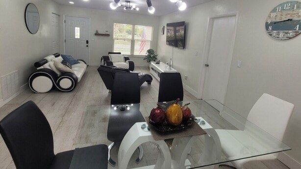 A modern living room with a glass dining table, black and white sofas, and a ceiling light fixture. - Tranquil 2-bedroom house with AC in Spring Hill (Spring Hill)