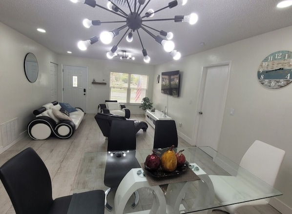 Ein modernes Wohnzimmer mit einem Glastisch, schwarzen und weißen Sofas und einer Deckenleuchte.