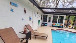 A poolside area with lounge chairs, a small table, and a pool. - Tranquil 2-bedroom house with AC in Spring Hill (Spring Hill)