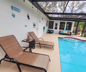 Ein Poolbereich mit Liegestühlen, einem kleinen Tisch und einem Pool.