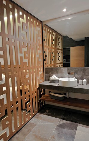 A modern bathroom with a wooden partition, a sink with a marble countertop, and a mirror above it. - Luxury Studio Private pool IIK C409SF (Tulum)