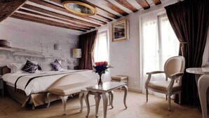 A hotel room with a bed, a chair, a small table, and a window with curtains. - Confidential Room 1, a Stone's Throw From the Louvre (Paris)