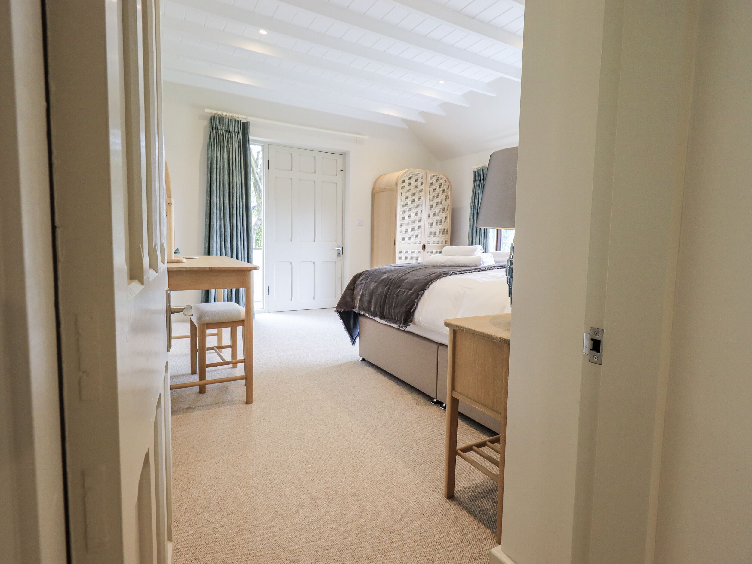A bedroom with a bed, bedside table, chair, and a door leading to another room.
