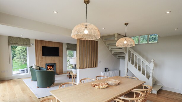 Een moderne eethoek met een houten tafel en stoelen, een open haard en een trap.