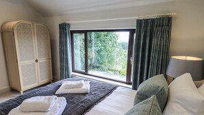 Een hotelkamer met een bed, een kledingkast, een raam met gordijnen en een lamp.