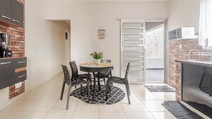 Una cocina compacta con comedor, que presenta una pared de ladrillo, una mesa redonda con sillas y una pequeña planta en maceta.