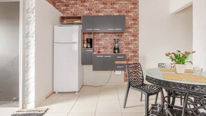 Una cocina compacta con un refrigerador blanco, gabinetes grises y una pared de ladrillo decorativa.