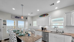 Una cocina moderna con armarios blancos, encimeras de granito y una isla central.