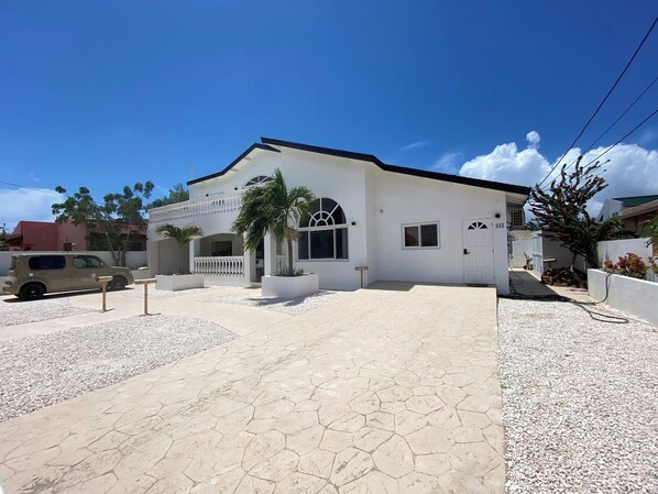 A two-story house with a covered patio, a driveway, and a small car parked in front.