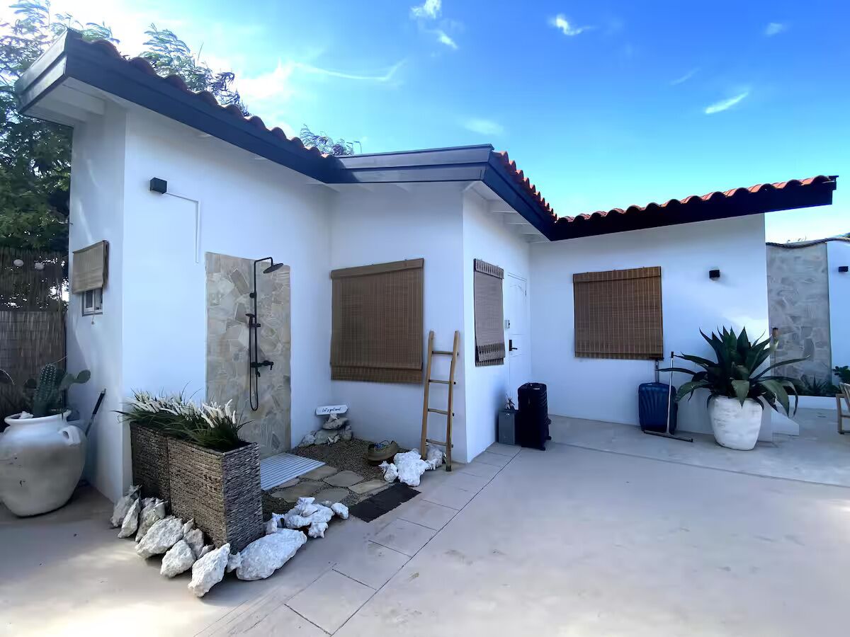 A modern house with a tiled roof, a small porch area, and potted plants.