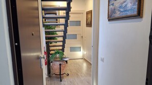 Ein Flur mit einer Holztreppe, einem Blumentopf und einem Bild an der Wand.