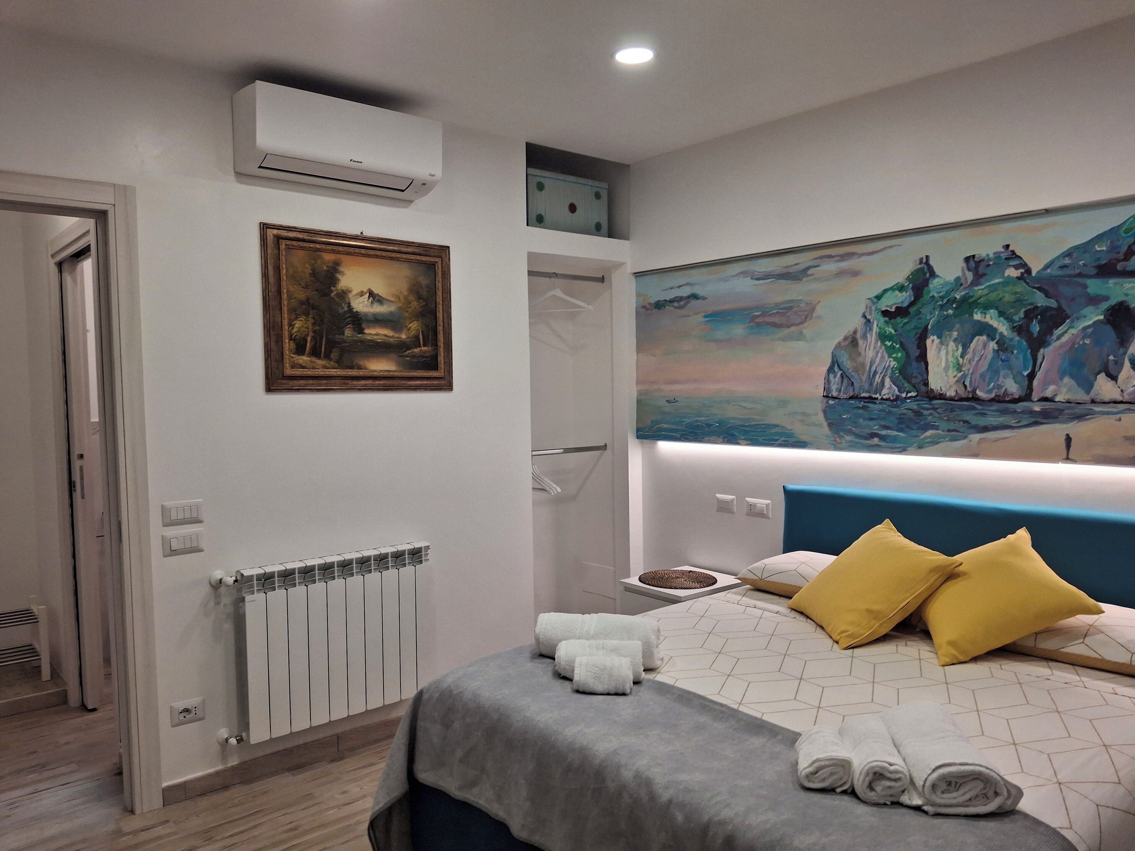 Una habitación de hotel moderna con una cama, un cuadro, un radiador y un equipo de aire acondicionado.