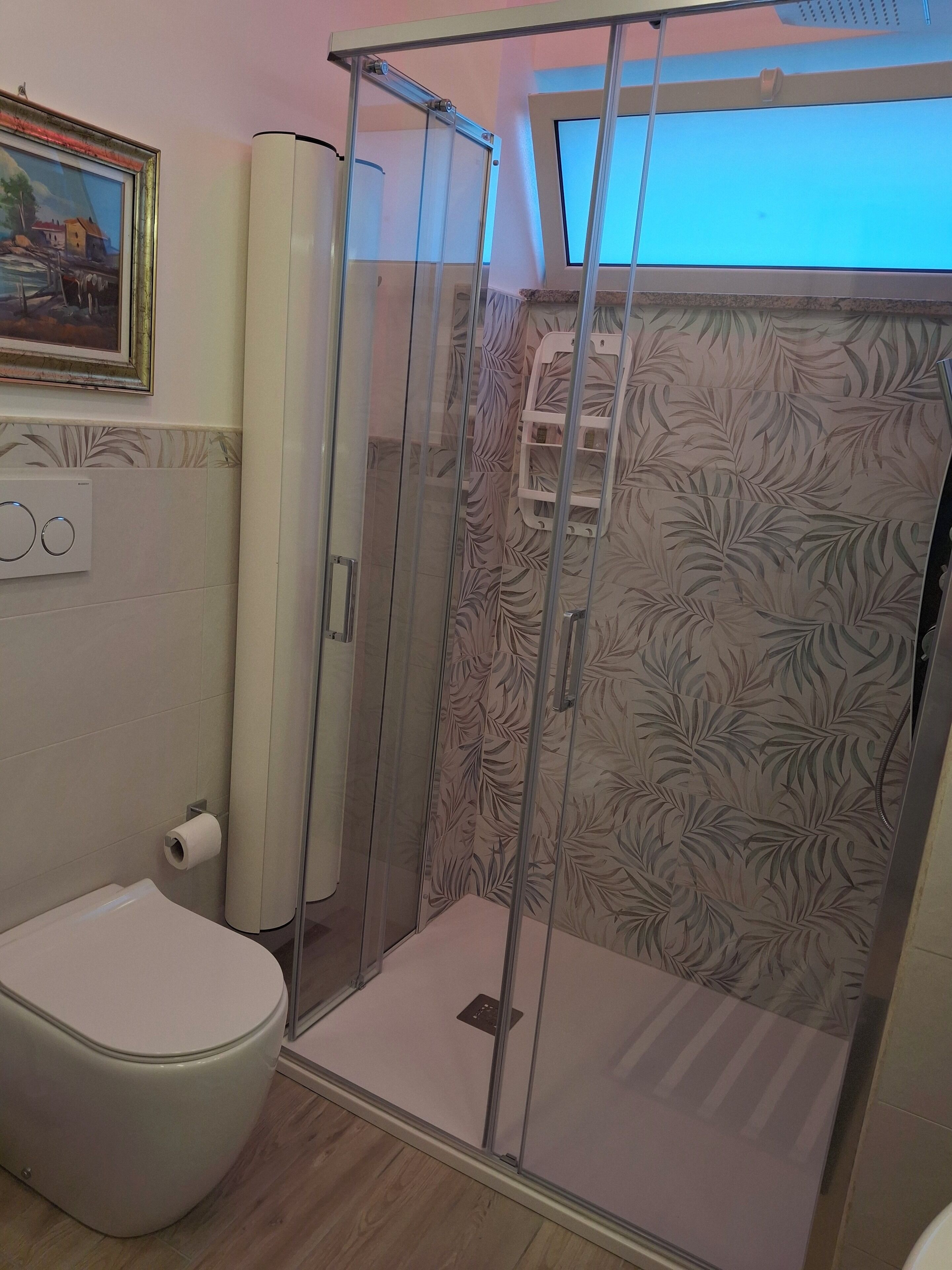 Ein Badezimmer mit Toilette, Duschkabine und einem Handtuchhalter an der Wand.