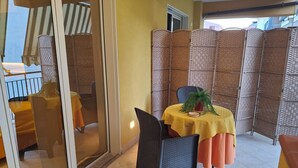 Ein Balkon mit Tisch, Stühlen und einem Blumentopf.