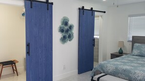 A bedroom with a bed, a nightstand, a lamp, a decorative wall piece, and a sliding door. - Cozy, bright, and spaciuos WF home with pool, dock, pool table & more. (Cape Coral)