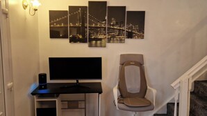 Ein Home-Office-Arbeitsplatz mit Schreibtisch, Computer und Stuhl, inklusive Stadtbild-Kunstwerk an der Wand.