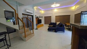 Ein modernes Wohnzimmer mit Treppe, einer Sofagarnitur und einem Flachbildfernseher.