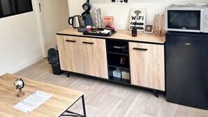 Una cocina moderna equipada con televisor de pantalla plana, cafetera, microondas y refrigerador compacto.