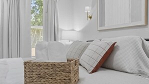 A neatly arranged bedroom with a bed, a woven basket, and a framed picture on the wall.