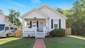 A single-story house with a front porch, a brick pathway leading to the entrance, and a vehicle parked to the left.