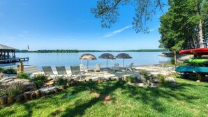 Un patio junto al lago con mobiliario exterior, sombrillas y kayaks.