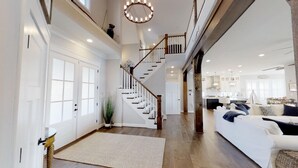 Un espacio habitable amplio con una escalera, un sofá grande y una cocina al fondo.