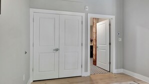 Un pasillo con dos puertas blancas, una de ellas da a una habitación con suelo estampado y un picaporte visible.