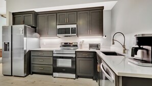 Una cocina moderna con electrodomésticos de acero inoxidable, muebles oscuros y una encimera elegante.