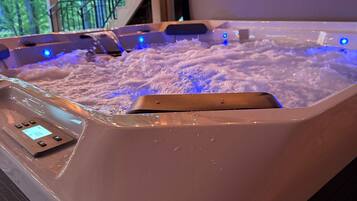 A hot tub with a control panel and LED lights, surrounded by wooden beams and a railing.