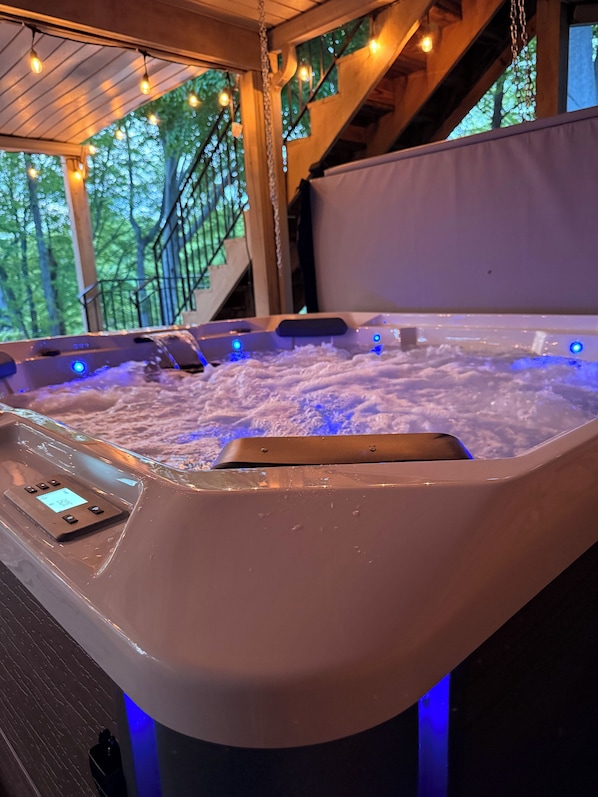 Un bain à remous doté d’un panneau de commande et de lumières LED, entouré de poutres en bois et d’une rambarde.