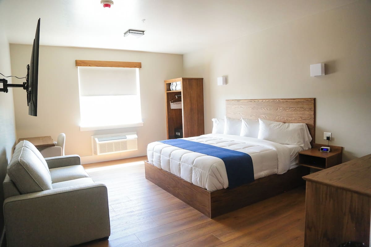 Une chambre à coucher comprenant un lit, une chaise, une armoire et un téléviseur.