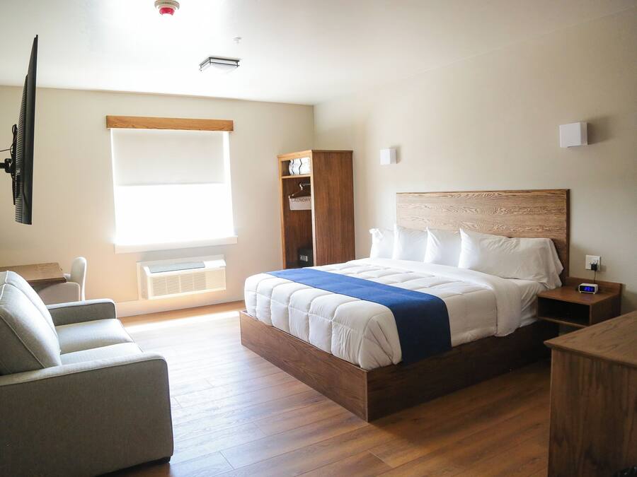A bedroom with a bed, a chair, a wardrobe, and a television.