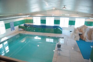 Una piscina interior con tabla de clavados, cartel de normas de seguridad y una formación rocosa.