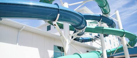Parque acuático con toboganes y un edificio al fondo.