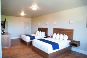 A hotel room with two beds, a wooden dresser, a flat-screen TV, and a small bedside table. - Splash Canyon Hotel (Twin Falls)