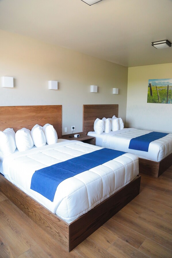 Two double beds with wooden headboards, white bedding, and blue throw blankets.