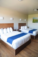Dos camas dobles con cabeceros de madera, ropa de cama blanca y mantas de color azul.