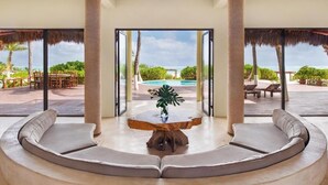 Un espacio de descanso circular con una mesa de madera y una planta, con vista a una piscina y mobiliario exterior.