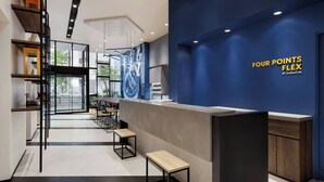 A modern interior with a reception desk, seating area, and a blue accent wall with the text "FOUR POINTS FLEX BY SHERATON". - Four Points Flex By Sheraton Tokyo Shibuya West (Tokyo)