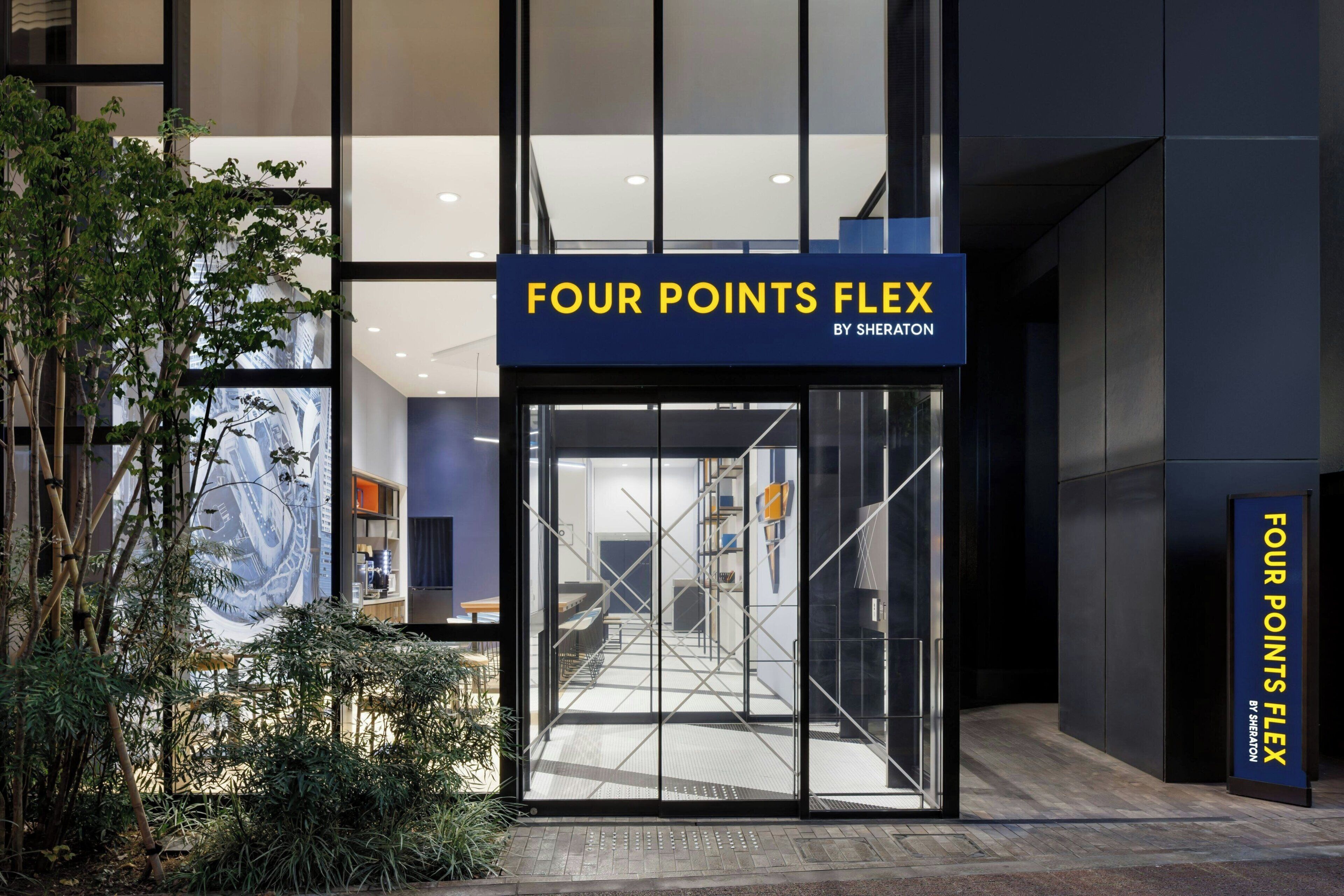 The entrance to the Four Points Flex hotel with a clear view of the interior through the glass doors.