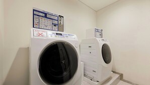 A laundry area with two washing machines and a control panel with instructions. - Four Points Flex By Sheraton Tokyo Shibuya West (Tokyo)