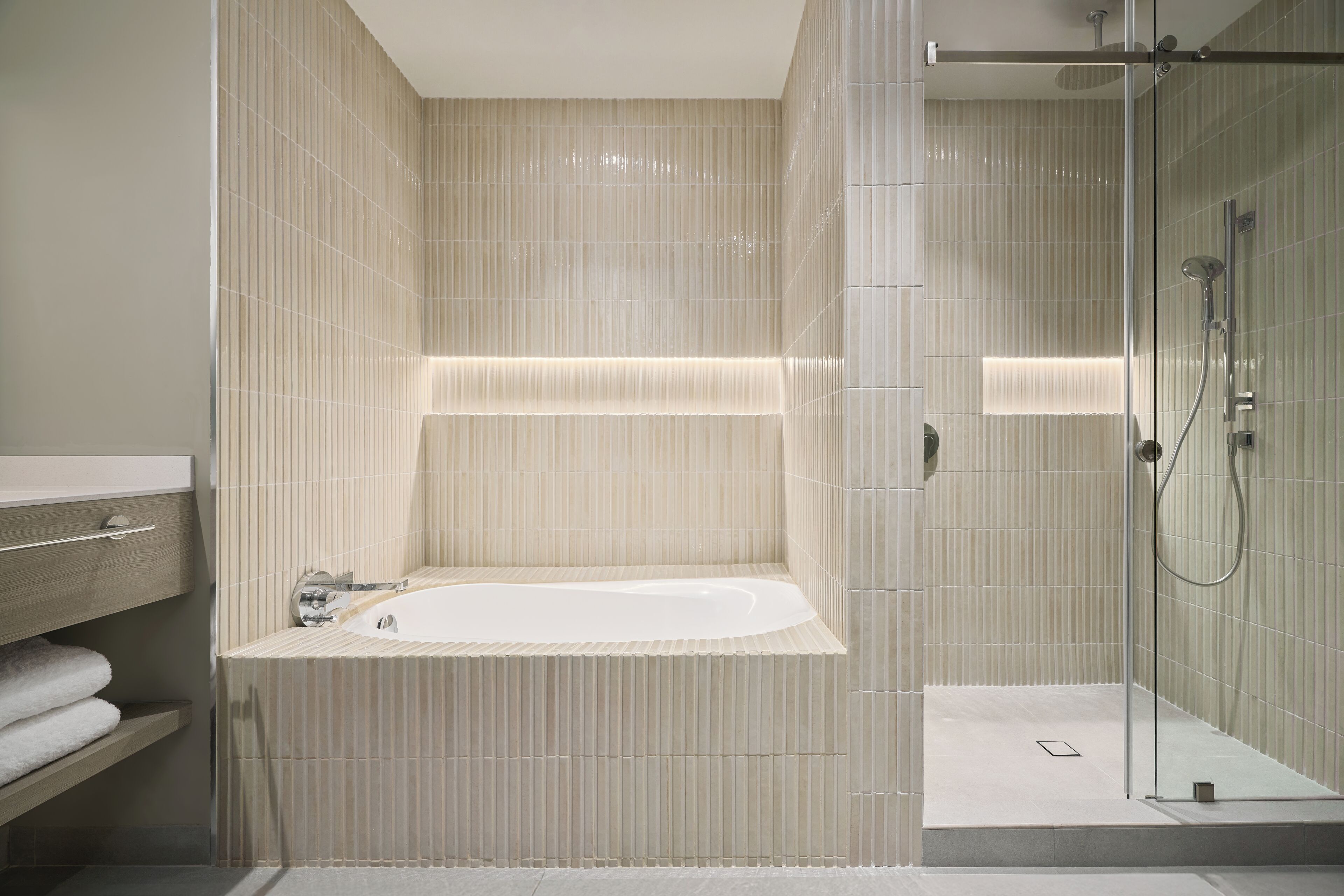 A modern bathroom with a freestanding bathtub, a glass shower enclosure, and a wooden vanity with a towel rack.