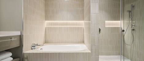 A modern bathroom with a freestanding bathtub, a glass shower enclosure, and a wooden vanity with a towel rack.