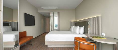 A modern hotel room with a bed, a desk, a chair, and a large window.