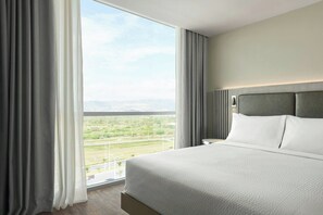 Una habitación de hotel con una cama grande, vistas a la ciudad y un cabecero moderno.